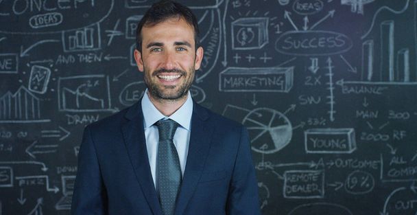 Portrait of a business man, a marketing teacher, draws a graph of success on a black board, on a black background. The concept: career growth, growth chart, successful man, marketing, ideas, finance. - Foto, Imagen
