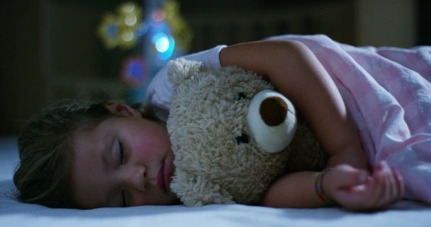 baby rests quietly in bed hugging a teddy bear toy, concept of peaceful dreams and homes without noise, happy children and mom and dad happy. happiness in sleep, children without coughing. - Foto, afbeelding