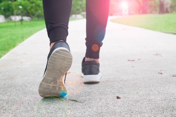 mulher fitness andando no parque público, close-up em sapato com luz solar
 - Foto, Imagem