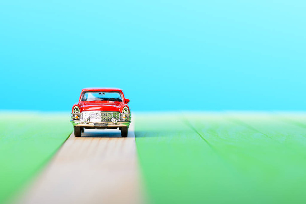 Красная винтажная модель автомобиля на деревянных досках
 - Фото, изображение