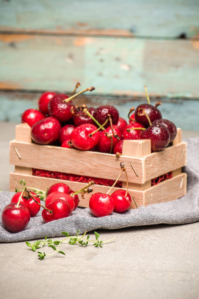Red ripe cherries in small wooden box - Foto, afbeelding