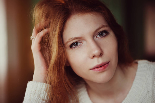 close up indoor portrait of adorable thoughtful young redhead woman with freckles and long hair - Foto, afbeelding