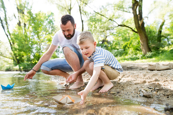 Young father with little boy at the river, sunny spring day. - Фото, изображение