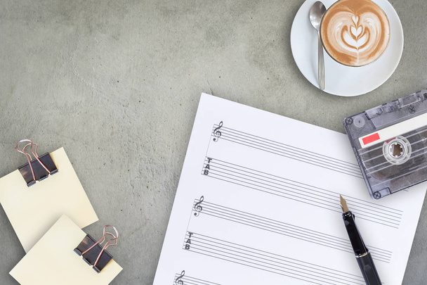 Sheet music, fountain pen, tape cassette and coffee latte on wooden table, top view picture - Photo, Image