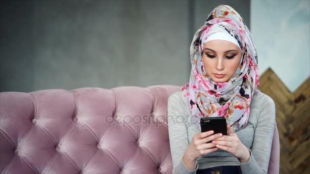 Mujer musulmana usando teléfono celular en casa
 - Metraje, vídeo