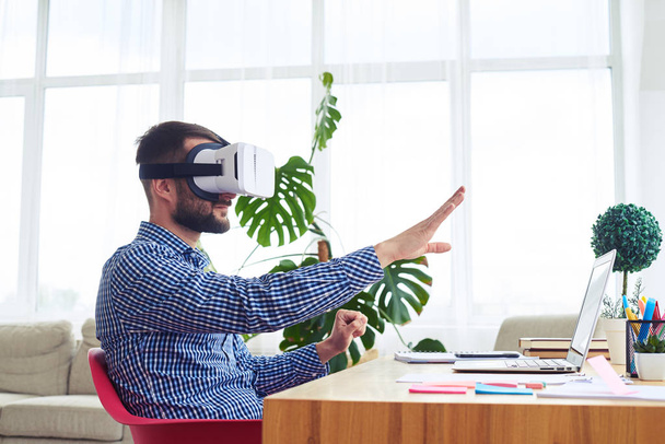 Мужчина в очках виртуальной реальности, ориентирующихся в пространстве, сидит на ta
 - Фото, изображение