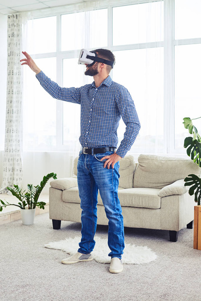 Sportive guy testing VR glasses in bright room - Foto, imagen