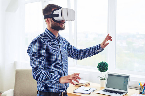 Good-looking guy with beard testing VR glasses at home - Foto, imagen