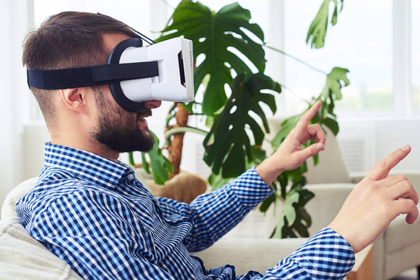 Stylish gentleman in virtual reality goggles sitting on sofa - Foto, immagini