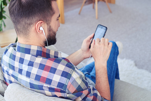 Tipo barbudo escuchando música con auriculares usando smartphone
 - Foto, imagen