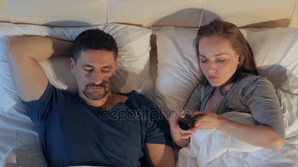 The couple quarreling sharing remote control, watching the TV. - Video