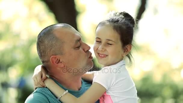 Hombre de mediana edad sostiene a una hija en sus brazos, la besa en la mejilla. Sonríen y ríen
. - Imágenes, Vídeo