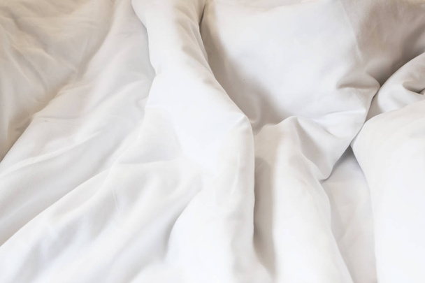 białą poduszkę na łóżku i z zmarszczek niechlujny koc w sypialni, przed spaniem w długa noc - Zdjęcie, obraz