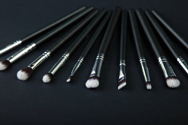 Professional makeup brushes on a black background, natural cloth - Foto, afbeelding
