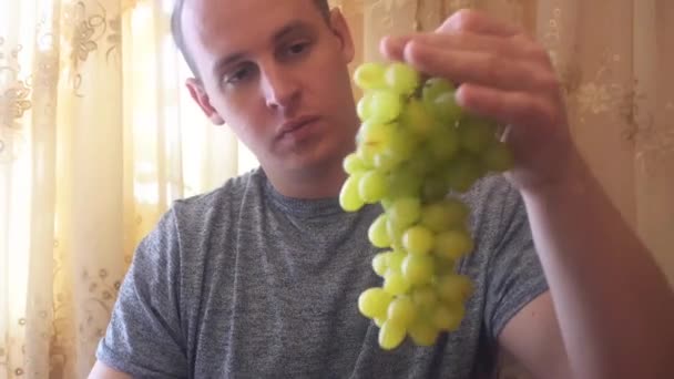 若い男が彼の手で緑のブドウを保持 - 映像、動画