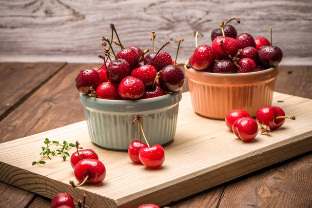 Red ripe cherries in ceramic bowls - Фото, изображение