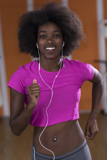 afro american woman running on a treadmill - Фото, изображение