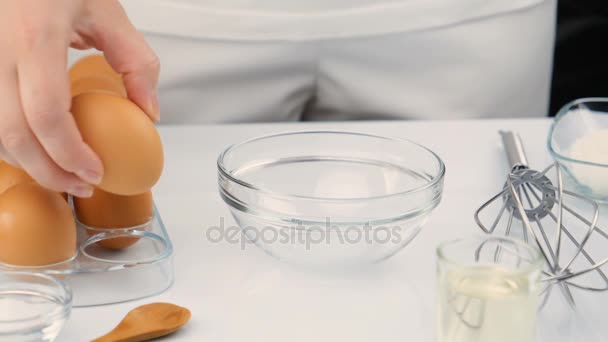 Breaking eggs in a glass bowl, slow motion - Materiał filmowy, wideo