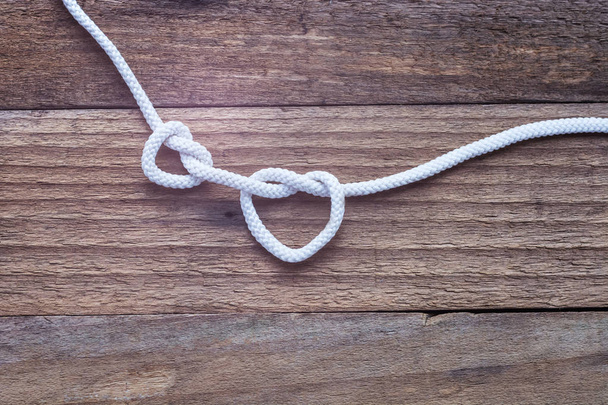 Two knot on rope a heart on vintage wooden background - Photo, Image