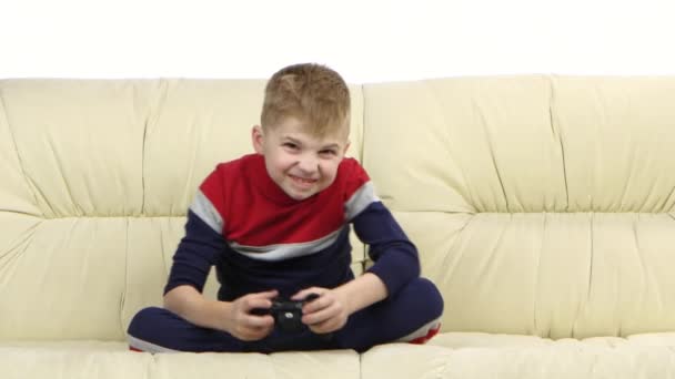 Boy with games console playing video game on the sofa - Video, Çekim