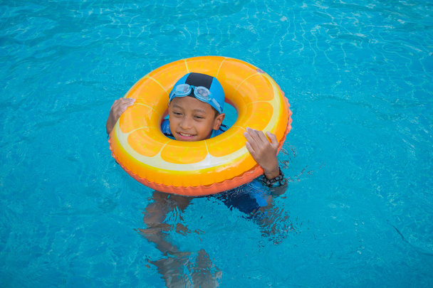 Jeune garçon nageant dans la piscine avec anneau de natation
 - Photo, image