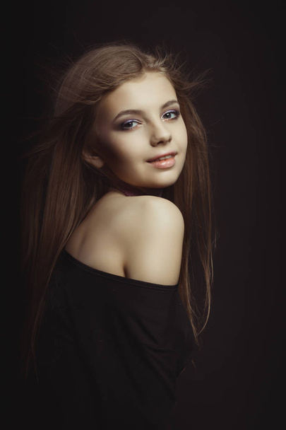 Sonriente joven modelo en vestido negro posando en el estudio
 - Foto, Imagen
