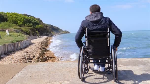 Espalda del hombre discapacitado en silla de ruedas en la playa cámara lenta
 - Metraje, vídeo
