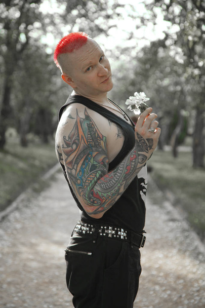 alternative tattoo rehead man walking on the apple tree park with flowers - Photo, Image