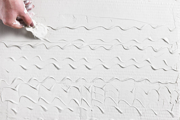 Hand with spatula make pattern on white plaster - Foto, Bild