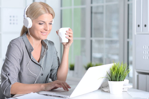  Laptopot használó nő fülhallgatóban - Fotó, kép