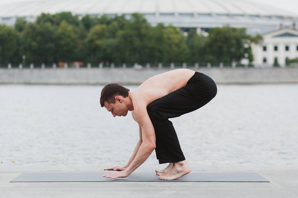 a young man practicing yoga asanas in the city on the waterfront - Foto, Imagem