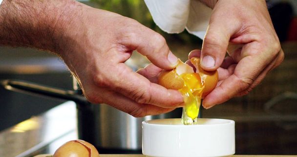 An Italian chef breaks and slams fresh egg yolk and bio with a fork, to mix and to use it as an ingredient to an Italian recipe.Concept of Italian food and gourmet , healthy diet and bio. - Фото, изображение