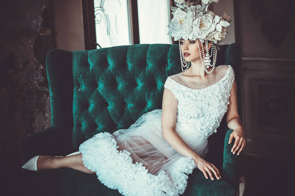 Beautiful bride sits on a chair. Luxury palace. - 写真・画像