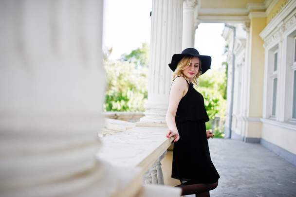 Blonde woman on black dress, necklaces and hat against vintage h - Foto, imagen