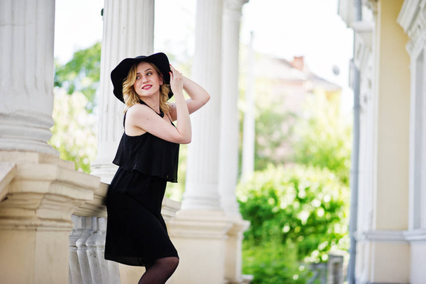 Blonde woman on black dress, necklaces and hat against vintage h - Foto, immagini