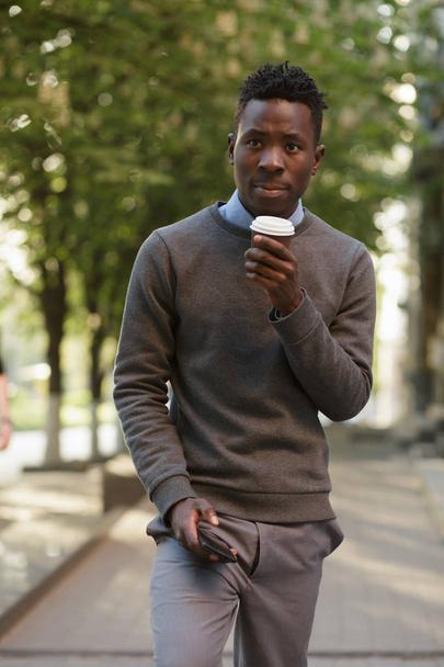African american man drinking tea in sunny evening city - Fotoğraf, Görsel