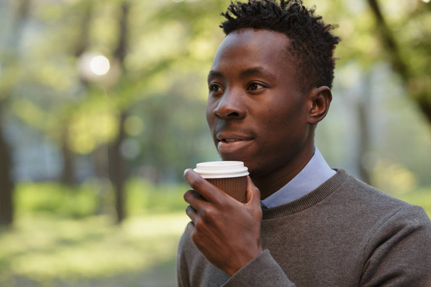African american man drinking tea in sunny evening city - Фото, изображение