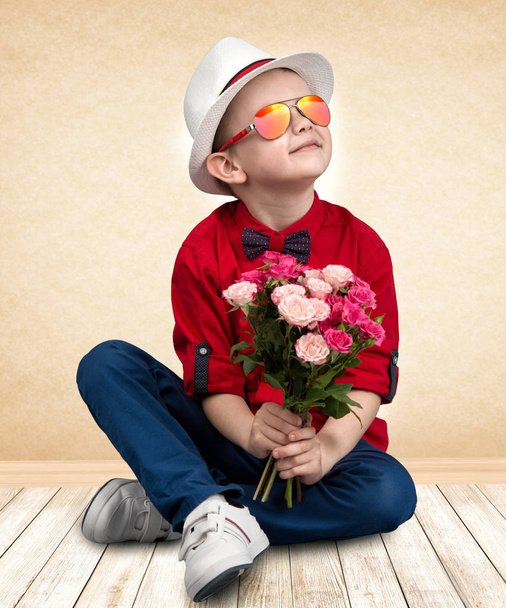 Stylish boy in a hat holding a bouquet of roses.Children's fashion - Foto, Imagen