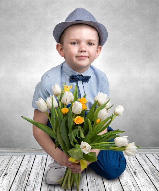 Stylish boy in a hat holding a bouquet of spring tulips.Children's fashion. - Foto, Imagen