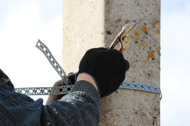 Werknemer brengt een metalen chroomklem aan op een paal voor het ophangen van een verkeersbord - Foto, afbeelding