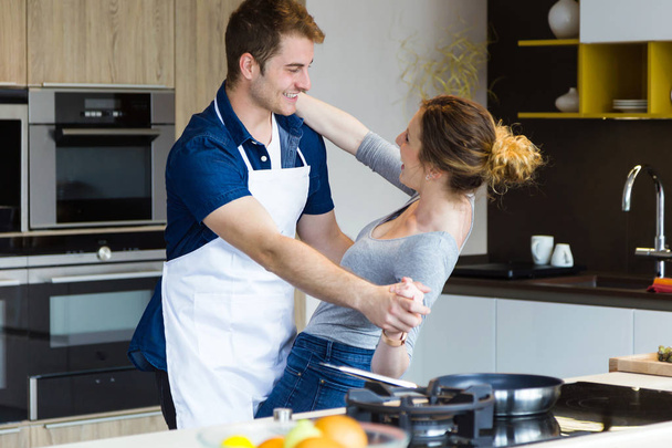 Красивая молодая пара веселится на кухне дома
. - Фото, изображение
