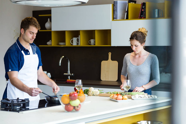 Happy young couple cooking together in the kitchen at home. - Fotoğraf, Görsel
