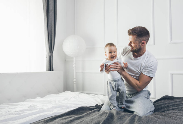 Happy father with his son playing at home on the bed - Foto, Bild