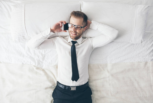 Top view. Handsome businessman with glasses lying on bed - Фото, зображення