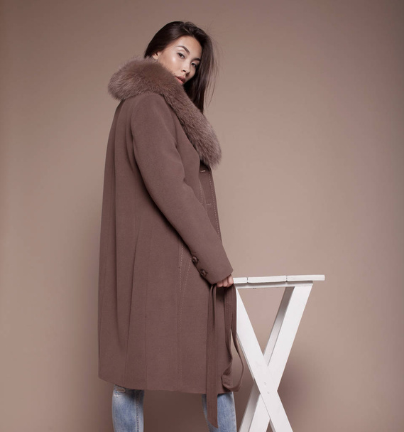 Winter Woman in Luxury Fur Coat. Fashion asian model om beige background. - Foto, afbeelding