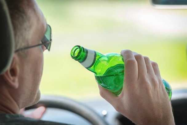 Ο άνθρωπος που πίνει μπύρα κατά την οδήγηση ενός αυτοκινήτου - Φωτογραφία, εικόνα