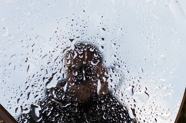 Reflexão silhueta homem irreconhecível em uma janela molhada
.  - Foto, Imagem