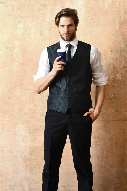 morning coffee, young serious business man holding paper cup - Foto, afbeelding