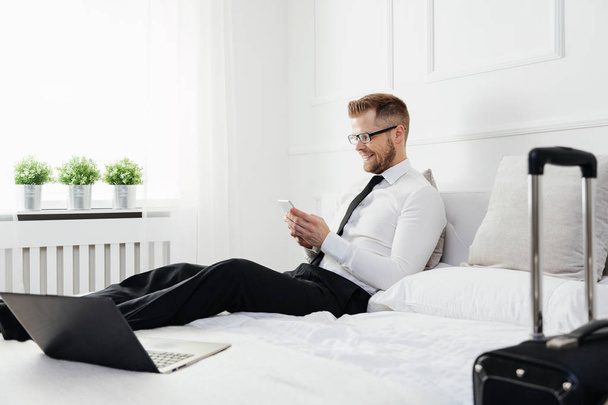 Businessman working from a hotel room with his mobile phone - Foto, Imagem