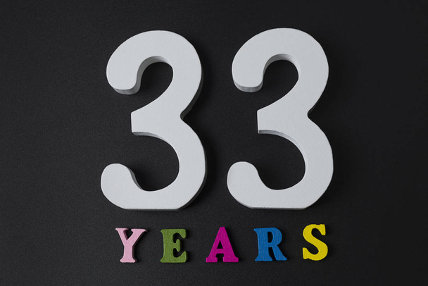 Γράμματα και αριθμοί τριάντα τρία χρόνια σε μαύρο φόντο. - Φωτογραφία, εικόνα
